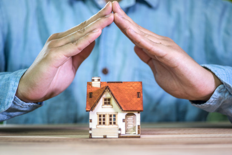 Hands protecting a miniature house
